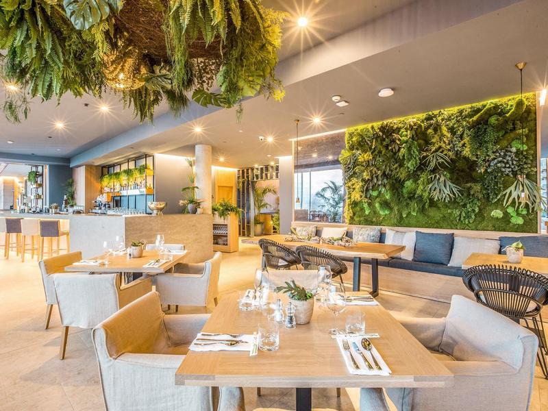 Bright hotel room with large bed, balcony, and sea view.