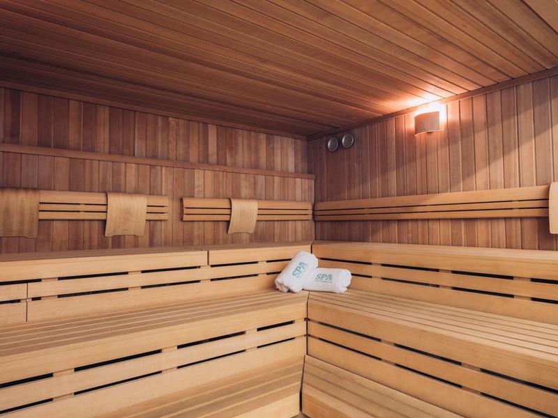 Spacious wooden sauna with benches and towels on a bench.