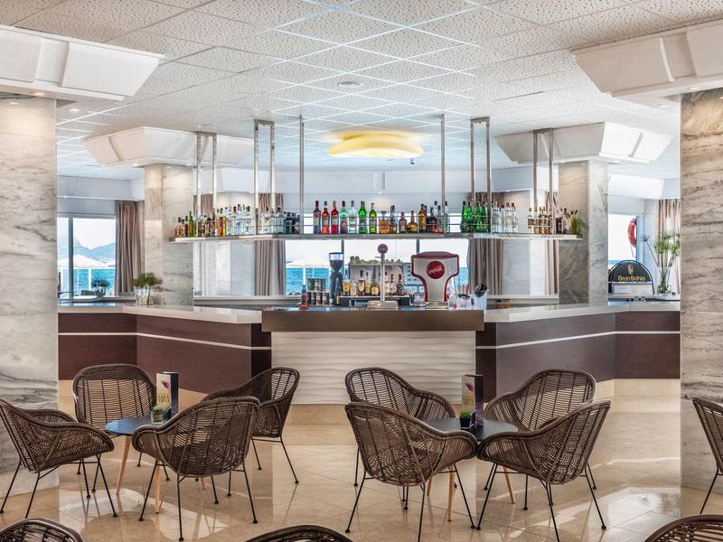 Modern hotel bar area with stylish dark chairs and an illuminated counter.