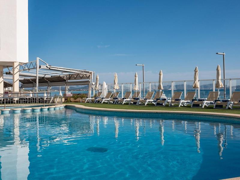 Modern pool area with lounge chairs and umbrellas under clear sky