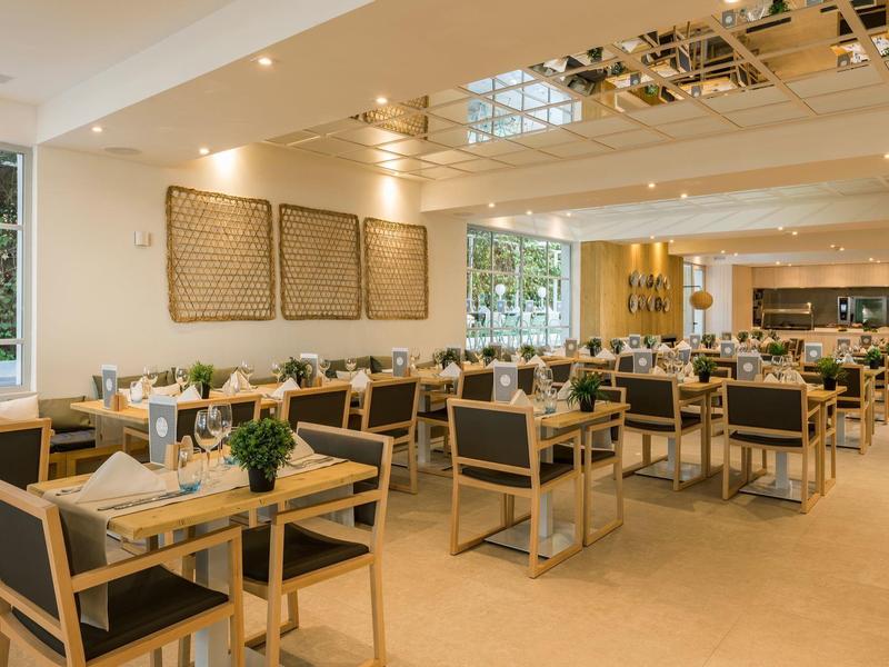 Salle à manger d'hôtel moderne avec tables en bois et chaises rembourrées.
