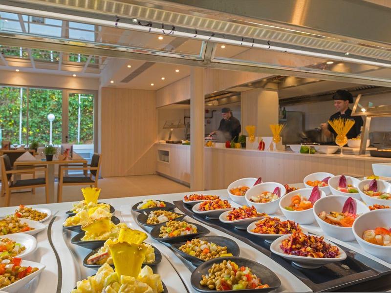 Grand buffet avec divers plats colorés dans un restaurant lumineux et moderne.