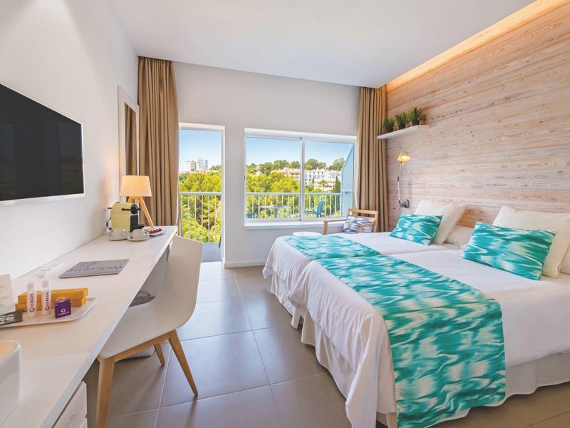 Chambre lumineuse avec lit double, bureau, télé, grandes fenêtres et décoration moderne.