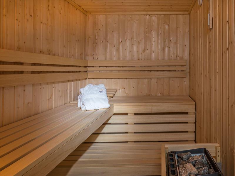 Sauna en bois avec petites serviettes blanches pliées sur un banc.