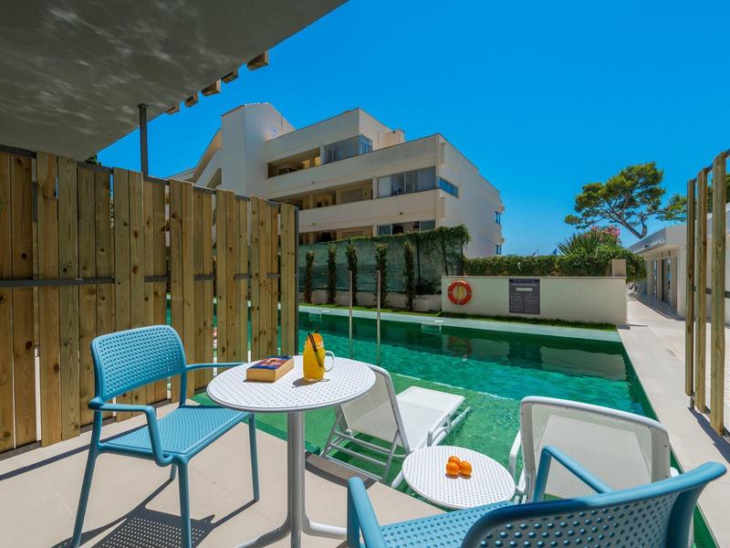 Terrasse avec tables et chaises bleues près d'une piscine dans un hôtel moderne.