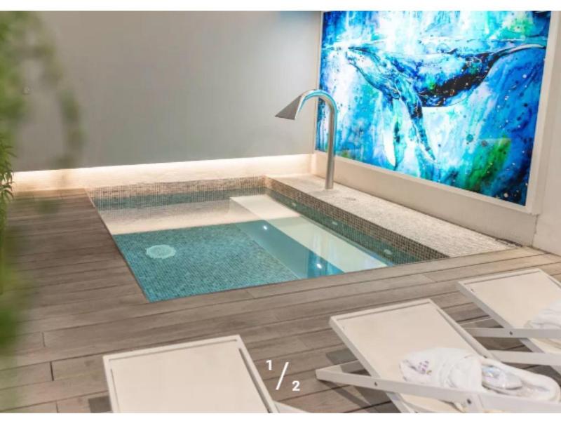 Piscine intérieure moderne avec eau claire, carrelage en bois et tableau artistique bleu.