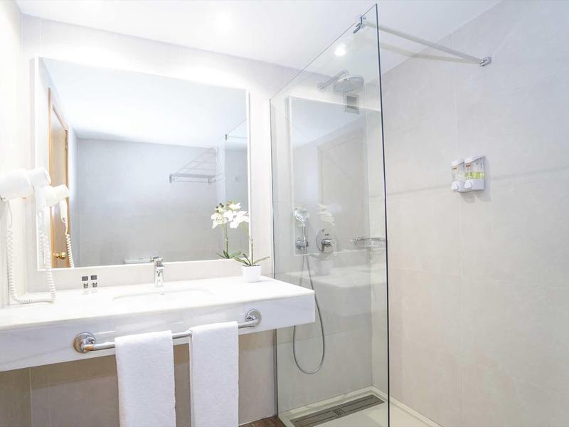 Bagno moderno con grande specchio, lavabo e cabina doccia in vetro.