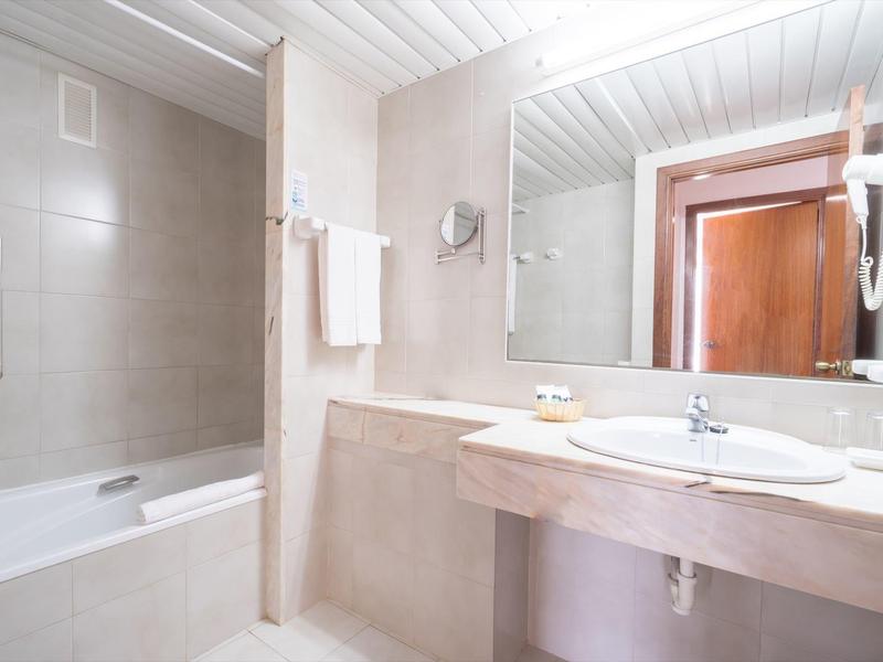 Bagno pulito con vasca da bagno, grande specchio e asciugamano bianco.