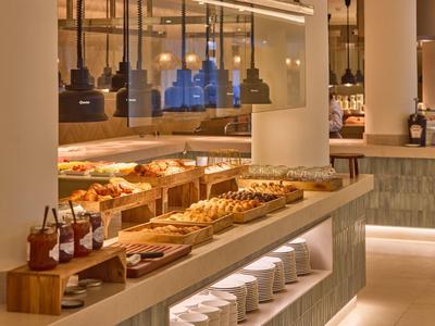 Bufet hotelowy z wyborem wypieków, dżemów i gorących dań w nowoczesnym otoczeniu.