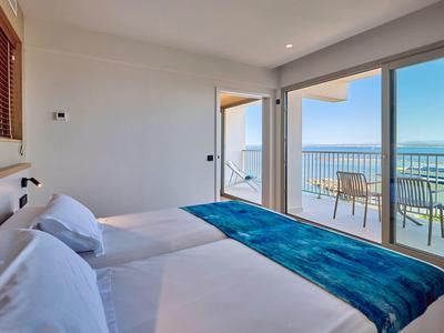 Nowoczesny pokój hotelowy z dwoma łóżkami i balkonem z widokiem na morze.