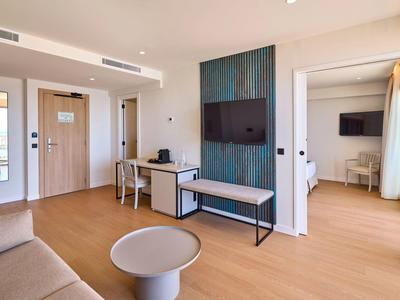 Nowoczesny salon pokoju hotelowego z telewizorem, biurkiem i dostępem do sypialni.