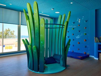 Pokój zabaw z zieloną, w kształcie rośliny, strukturą do wspinaczki i kolorowymi dekoracjami ściennymi w hotelu