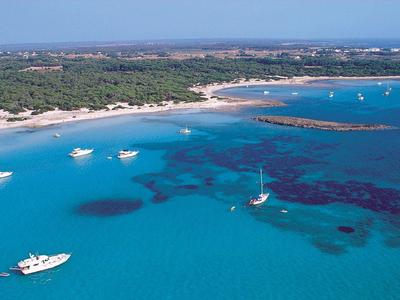 Przejrzysta turkusowa woda z kilkoma łodziami przy zalesionym wybrzeżu.