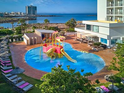 Kolorowy plac zabaw wodny z zjeżdżalniami obok hotelu i morza w tle