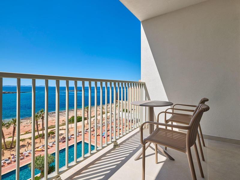 Balkon z dwoma krzesłami z widokiem na plażę i morze pod czystym niebem.