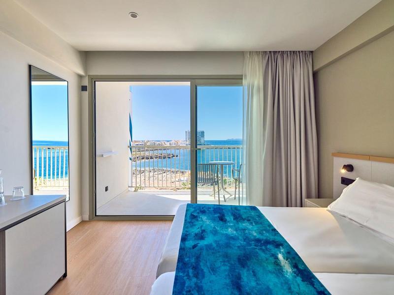 Pokój hotelowy z łóżkiem podwójnym, balkonem i widokiem na morze.