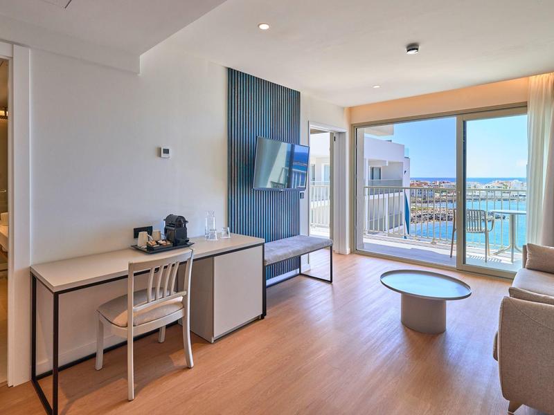 Nowoczesny pokój hotelowy z biurkiem, sofą i balkonem z widokiem na morze.