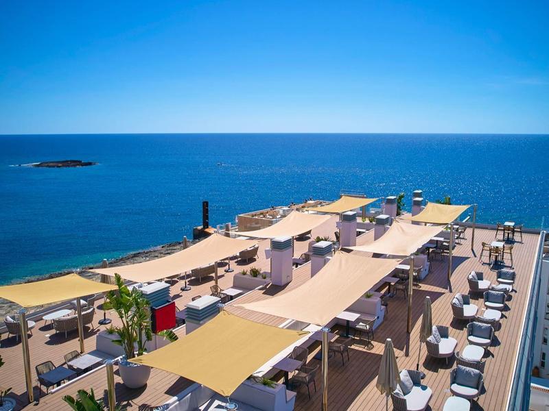 Taras na dachu z markizami i miejscami do siedzenia z widokiem na niebieskie morze pod czystym niebem