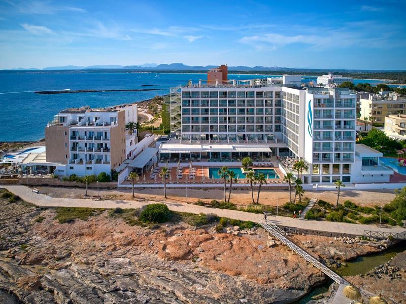 Nowoczesny kompleks hotelowy nad morzem z basenem i widokiem na wybrzeże przy czystym niebie.