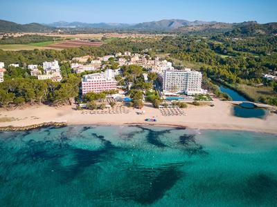 Ośrodek hotelowy przy piaszczystej plaży z turkusową wodą i zielenią wokół