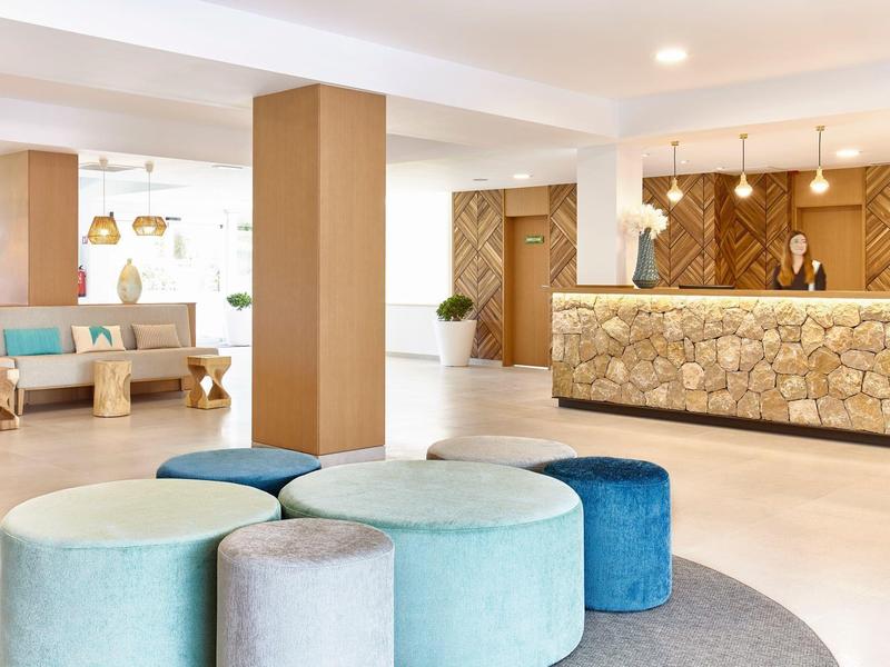 Světlá hotelová lobby s moderním posezením a kamennou recepcí.