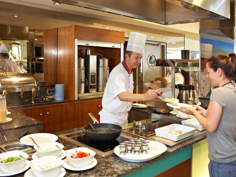 Kuchař obsluhuje hosty u bufetového pultu v hotelové kuchyni.