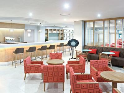 Nowoczesny bar hotelowy z wygodnymi czerwonymi fotelami i jasnym drewnianym barem.