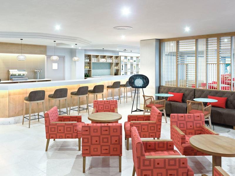 Nowoczesny bar hotelowy z wygodnymi czerwonymi fotelami i jasnym drewnianym barem.