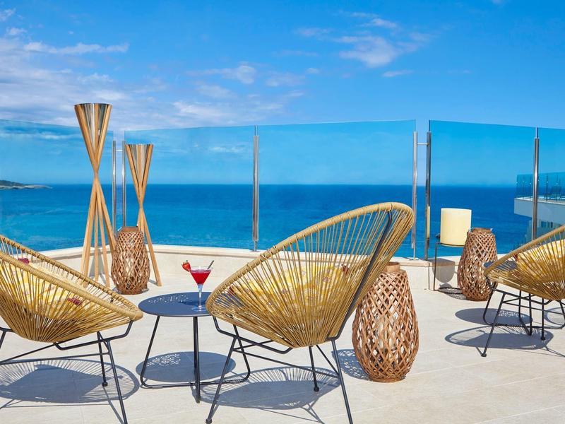 Taras na dachu z wiklinowymi fotelami i widokiem na morze przy czystym niebie.