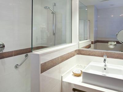 Moderne badkamer met wastafel, spiegel en glazen bad-douche ruimte.