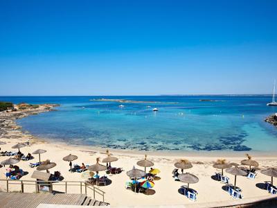 Plage avec parasols et chaises longues au bord d'une mer bleue calme sous un ciel clair.
