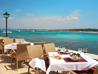 Terrazza di un ristorante con tavoli e sedie sul mare con acqua limpida.