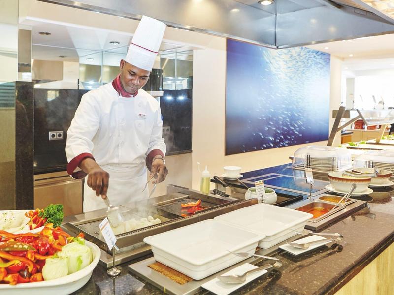 Chef kookt bij een buffet met diverse gerechten en serveerschalen.