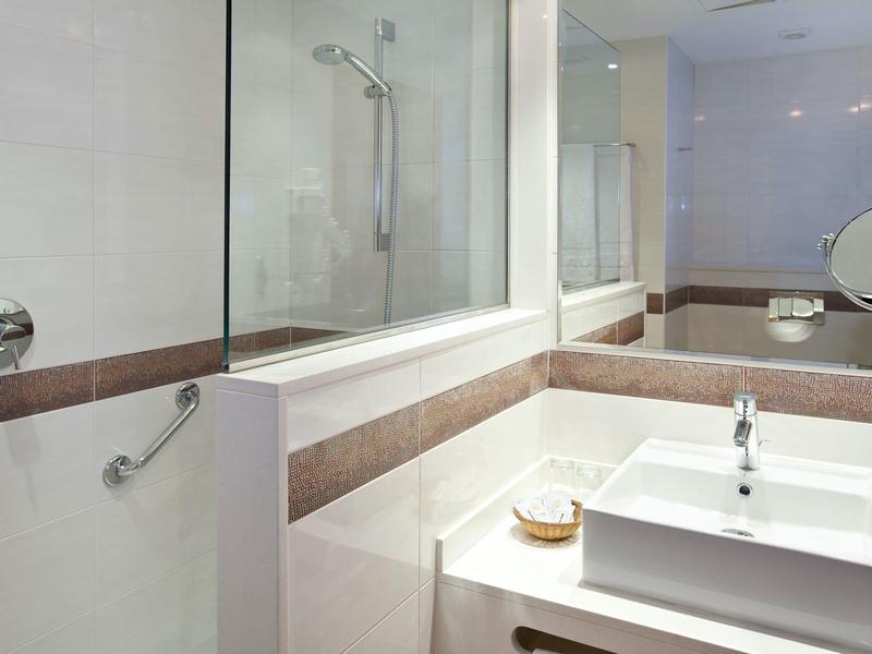 Moderne badkamer met wastafel, spiegel en glazen bad-douche ruimte.