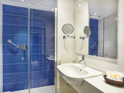 Modern hotel bathroom with blue-tiled shower and white sink countertop.