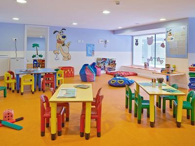 Sala giochi colorata e ben attrezzata per bambini con tavoli, sedie e giocattoli.
