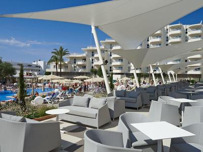 Area esterna moderna con posti a sedere e vista sulla piscina e balconi dell'hotel in una giornata di sole.