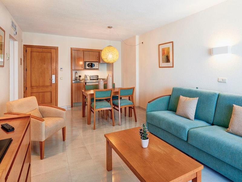 Soggiorno accogliente con divano blu, tavolo da pranzo e angolo cottura in appartamento moderno.