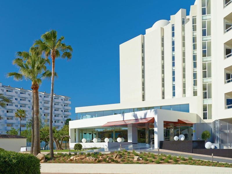 Edificio di hotel moderno con palme e cielo soleggiato sullo sfondo.
