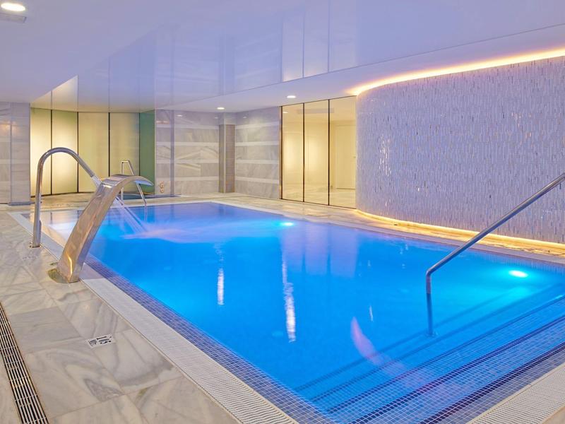 Piscina coperta con acqua blu e illuminazione moderna.