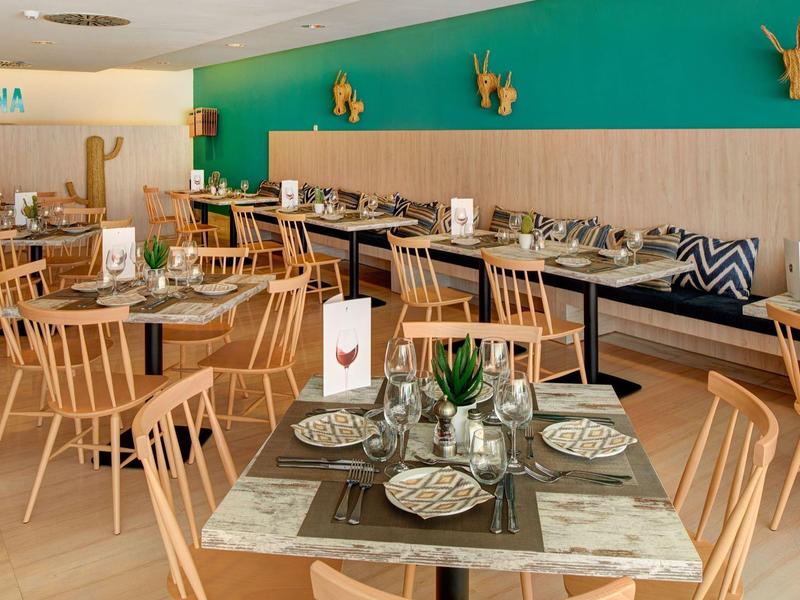 Ristorante moderno con mobili in legno, parete verde accentuata e tavoli elegantemente apparecchiati.