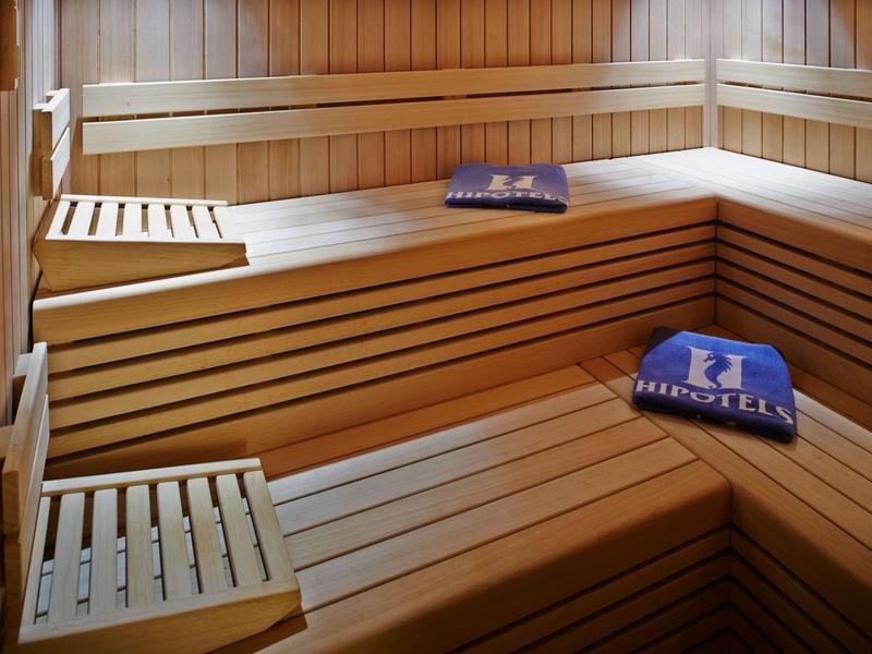 Interno di una sauna con panchine in legno e asciugamani blu.