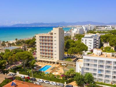 Budynki hotelowe z basenem w pobliżu plaży i widokiem na niebieskie morze i góry.