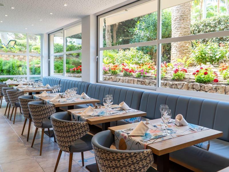 Nowoczesna restauracja z dużymi oknami i nakrytymi stolikami przy kanapie.