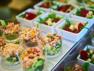 Close-up van verse salades geserveerd in doorzichtige en witte vierkante bakjes.