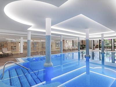 Modern overdekt zwembad met blauwe lichtstroken in het water en stijlvolle plafondverlichting.