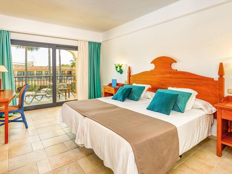 Hotelkamer met twee eenpersoonsbedden, houten meubels, balkon en lichte tegelvloer.