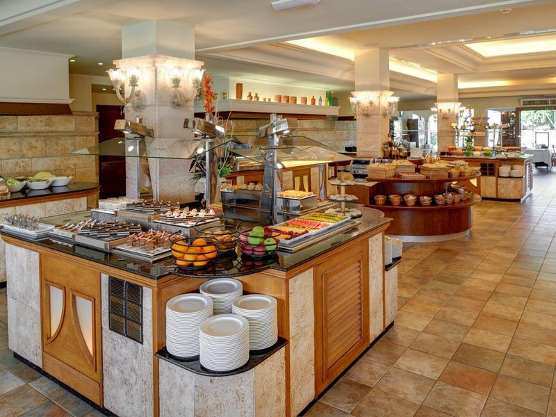Ruim buffetgedeelte in een hotel met diverse eetbar en warme verlichting.