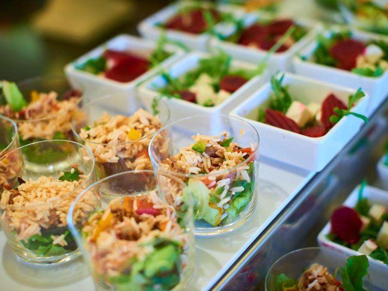 Close-up van verse salades geserveerd in doorzichtige en witte vierkante bakjes.