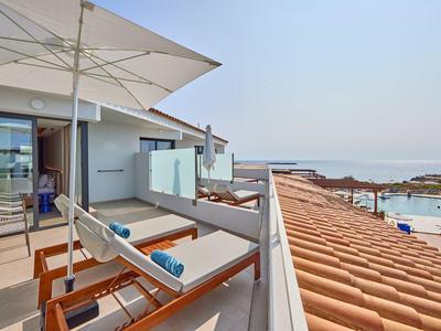 Balcony with sunbeds, umbrella, and sea view from a hotel room.